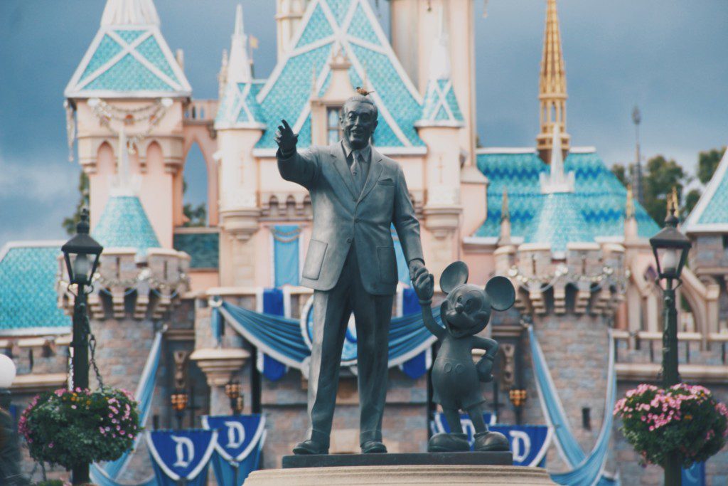 statue of walt disney and mickey mouse holding hands outside of disney world castle in orlando florida
