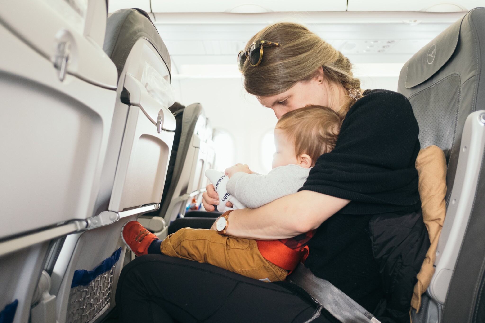 toddler baby sitting on mother's lap on the plane