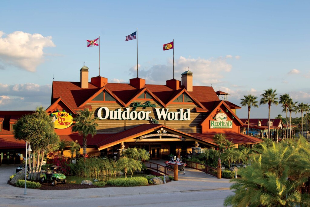 exterior view of bass pro shop in orlando florida, three flag on the roof during the day, with outdoor world on the sign